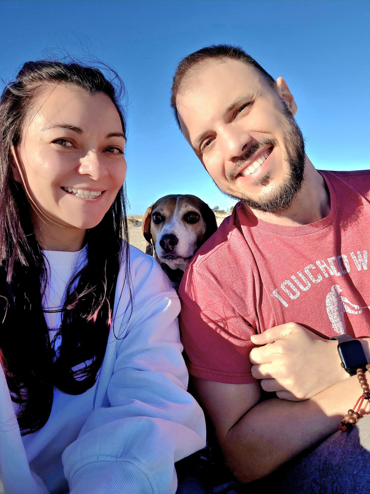 A man and woman pose for a selfie with a dog in the middle