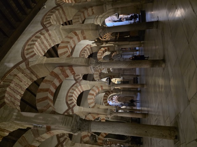 Interior of the Mezquita-Catedral in Córdoba Spain showing rows of iconic double-tiered horseshoe arches with red and white striped stonework and marble columns
