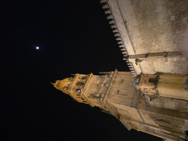 Bell tower of the Mezquita-Catedral in Córdoba Spain illuminated at night against a dark sky with the moon visible above