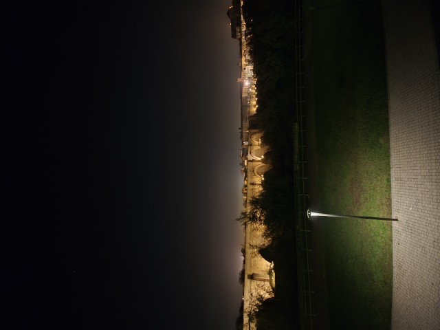 Roman Bridge of Córdoba Spain illuminated at night reflecting over the Guadalquivir River viewed from the riverbank