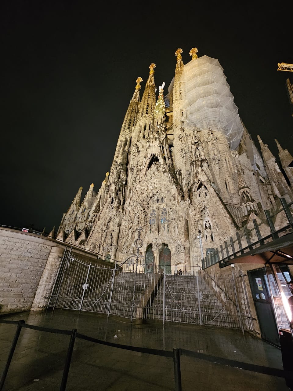 An eye-level, low-angle shot at night captures the intricate, sculptural details of the Sagrada Familia basilica in Barcelona, Spain
