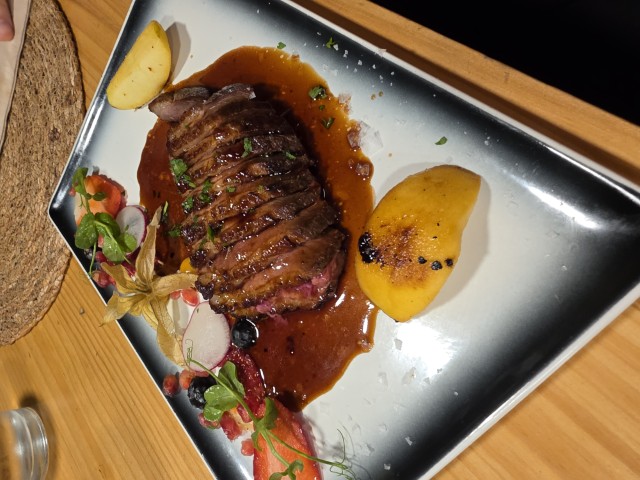 A square plate with a duck breast and sauce