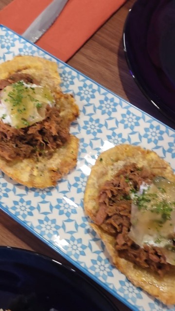 A blue and white plate with fried plantains and shredded pork. 