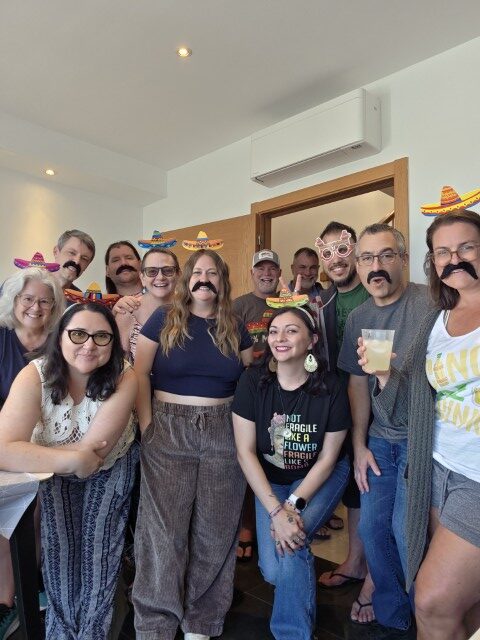 Group of expat friends wearing sombrero and mustache props at a party in Tavira Portugal