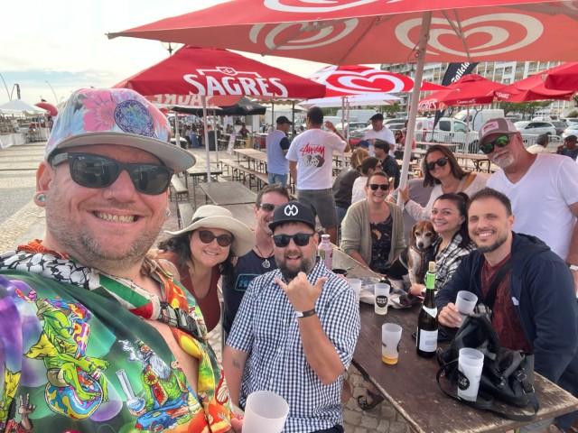 Group of expat friends with a beagle at an outdoor festival in the Algarve Portugal with Sagres beer umbrellas