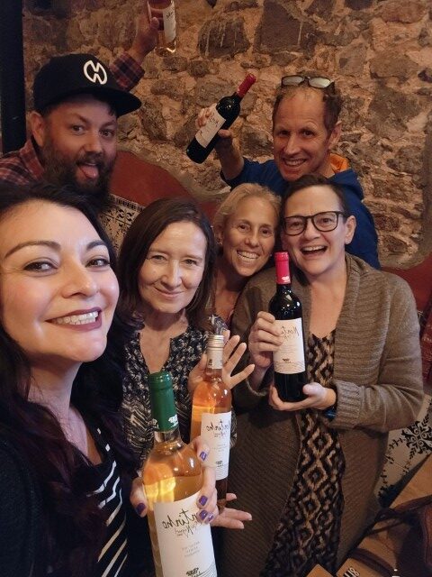 Group of expat friends celebrating a pub quiz win holding wine bottles at the Black Anchor Tavira