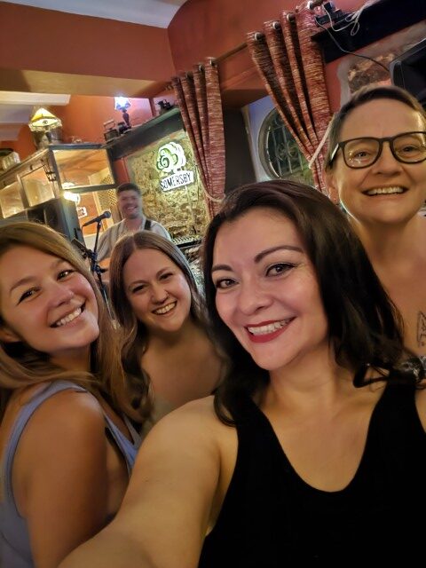 Group of women taking a selfie at the Black Anchor Irish pub in Tavira Portugal with Gary Vesey playing his guitar 